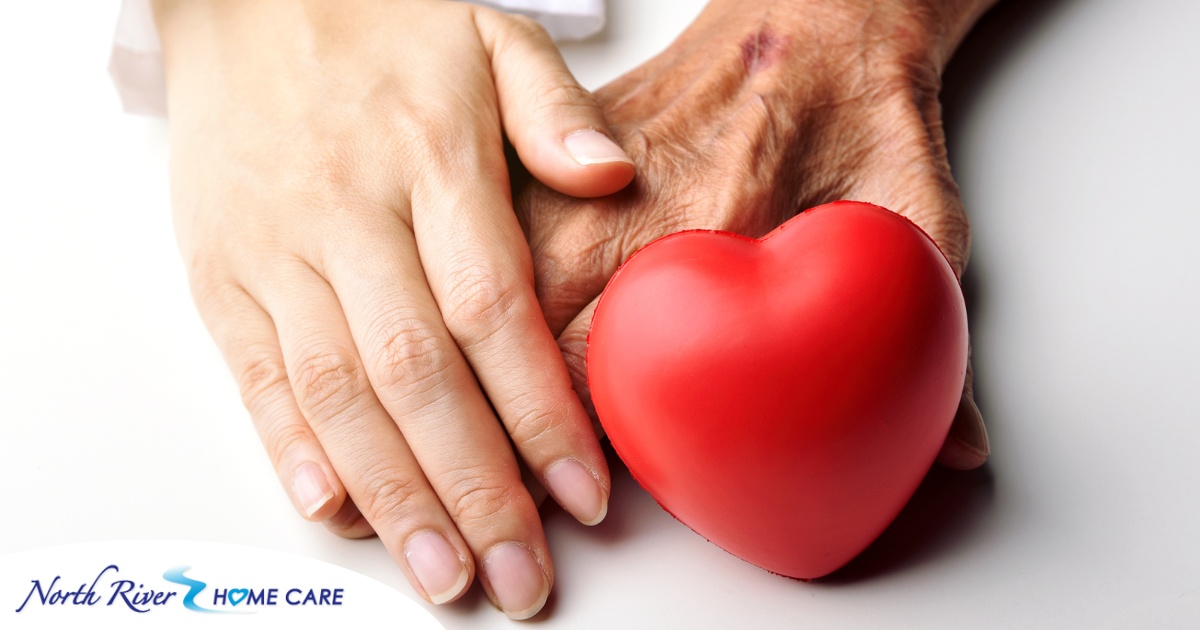 An old hand and a young hand with a heart represent caregiving.