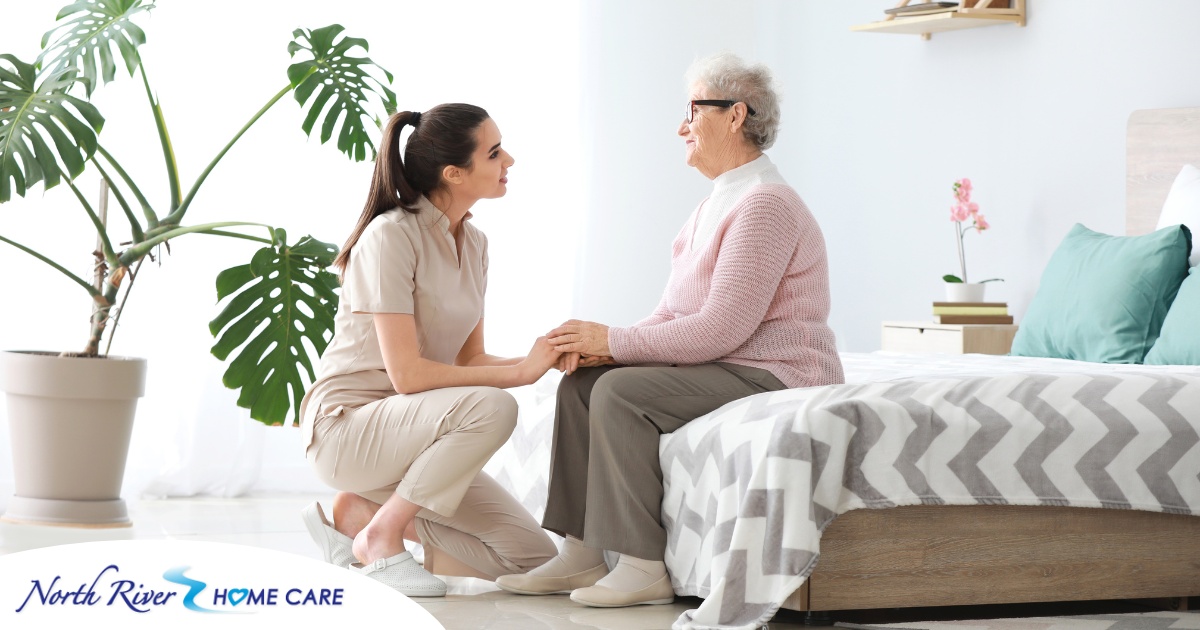 Communicating as a caregiver involves patiently and compassionately listening, as this caregiver is doing with her senior client.