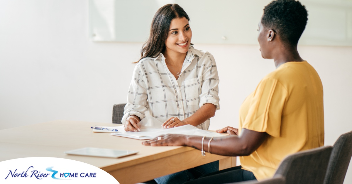 A woman happily interviews another woman, representing how well caregiver interviews can go when prepared.