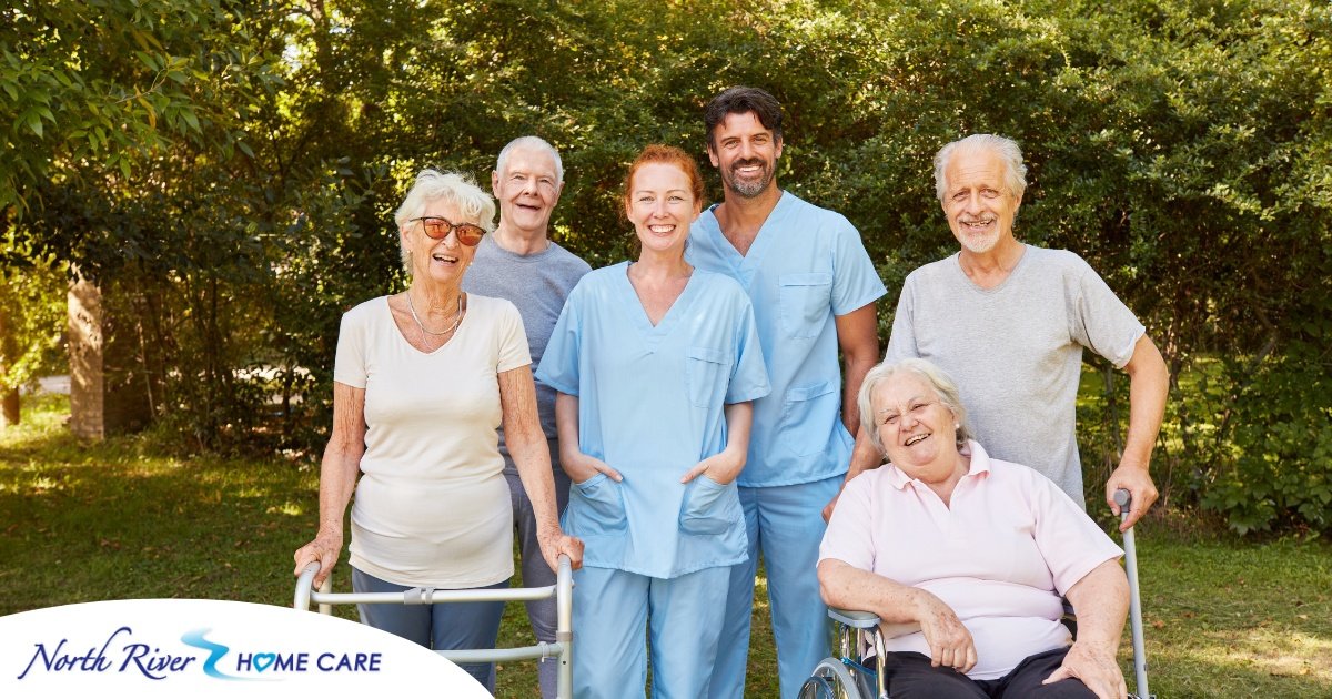 2 caregivers and seniors smile while in a group representing how caregivers can facilitate socialization.