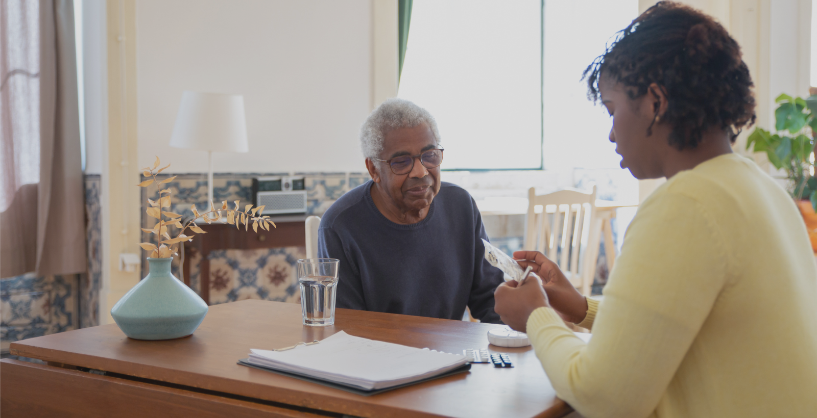 home health professional helping elderly man with medication reminder