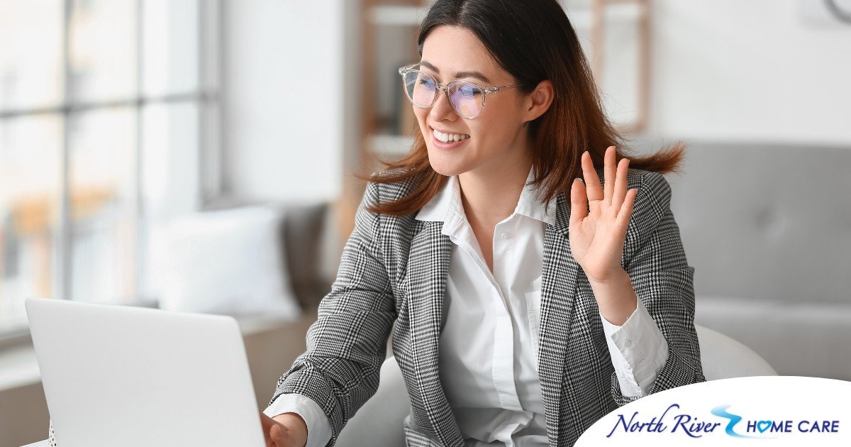 A well-dressed woman smiles and says hi on a videoconference, representing a candidate who is well-prepared for a caregiver interview.