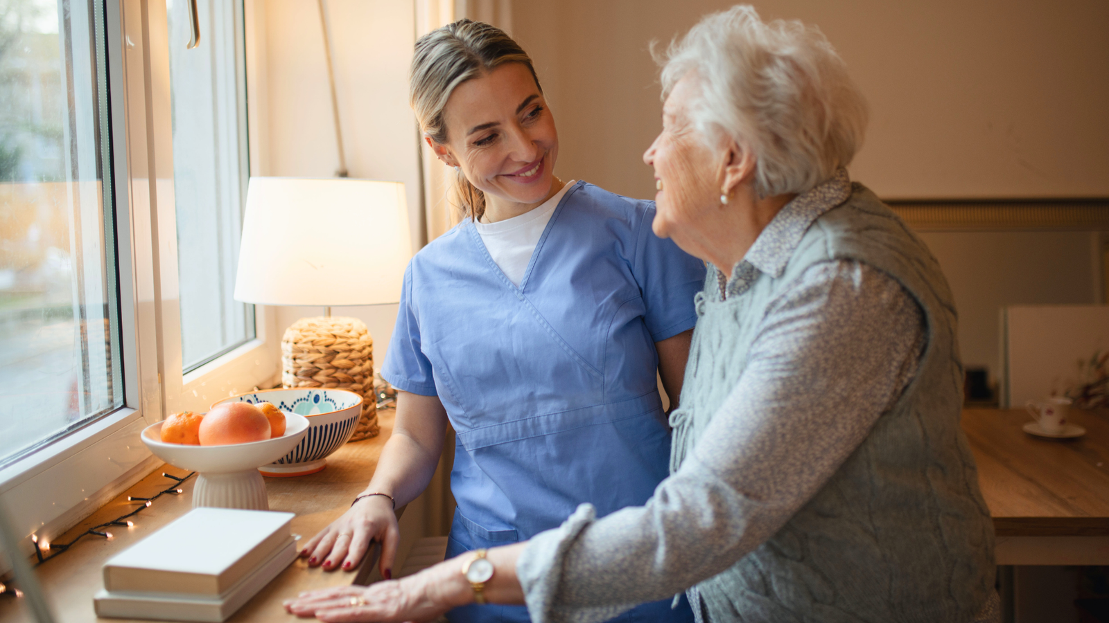 home caregiver helping senior woman in the kitchen 